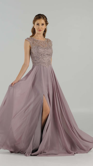 Woman in a lavender lace-shouldered evening gown with a high slit, standing and lifting the skirt in a studio.