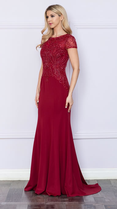 Full-length burgundy evening gown with intricate lace bodice and short lace sleeves, worn by a blonde woman posing against a light wall.